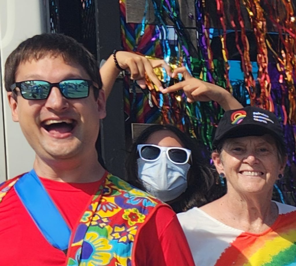 Selfie of 3 people, the center person is making a finger heart with both hands