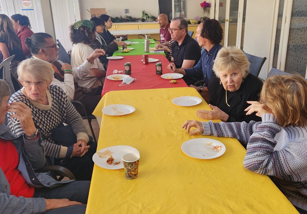 Table with colorful tablecloths and people discussing the workshop on the patio