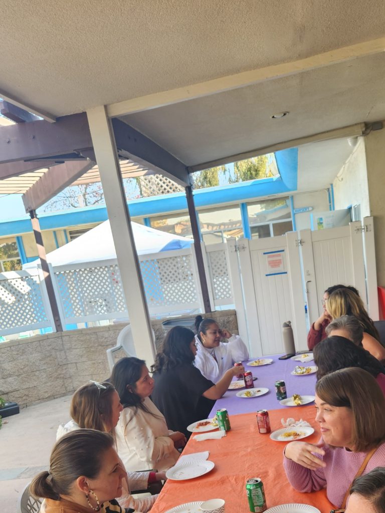 Table with colorful tablecloths and people discussing the workshop on the patio (different perspective)