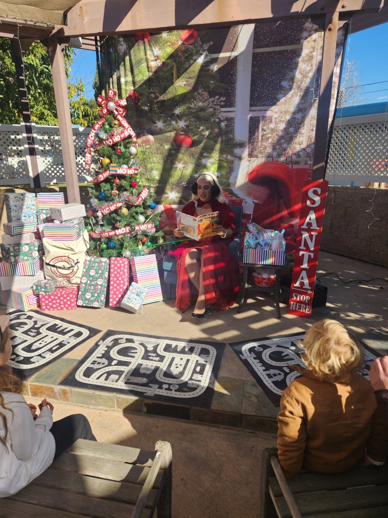 Mrs. Claus reading from santa's seat by the tree to the kids with a full view of the tree and presents