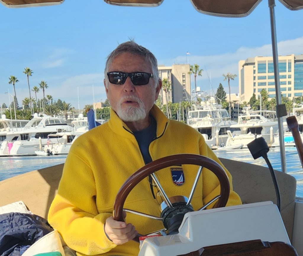 Gary in a yellow jacket as the wheel of a boat.